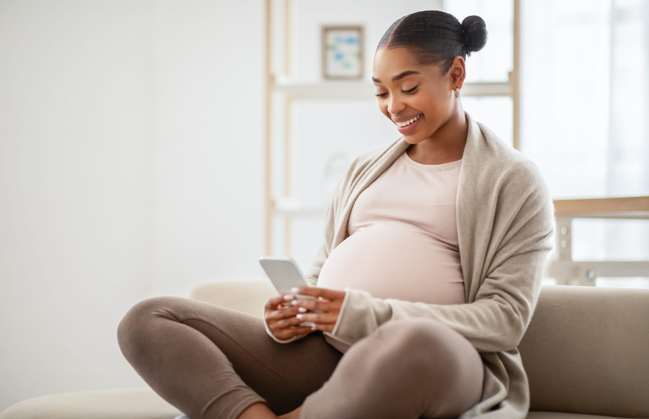 Black pregnant woman, warm and at ease, on her phone