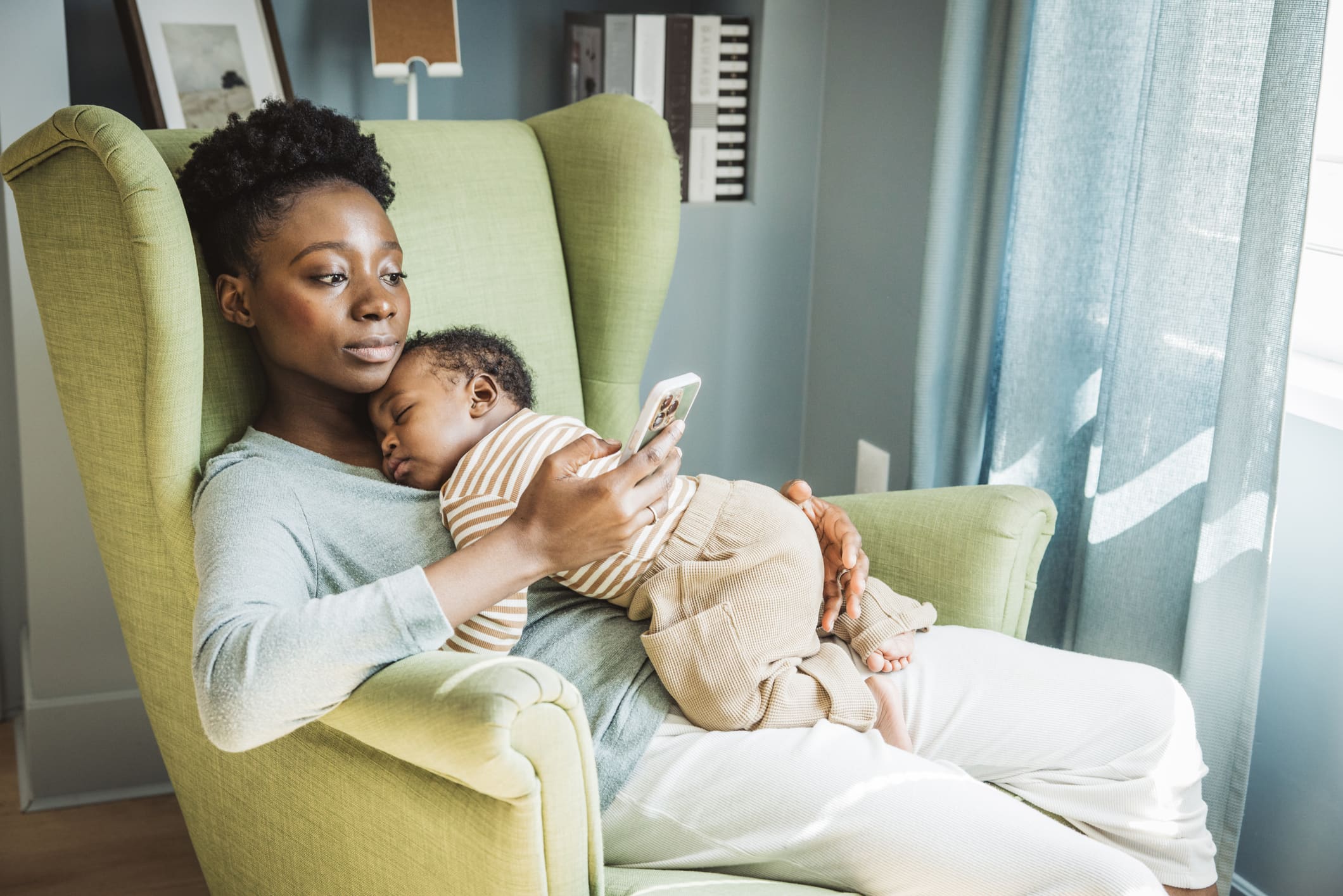 Black postpartum mother holding sleeping newborn, quiet and tender